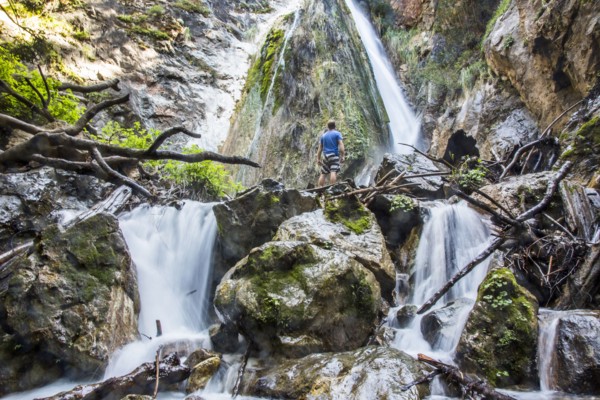 Caucasian man standing on rocks watching waterfall