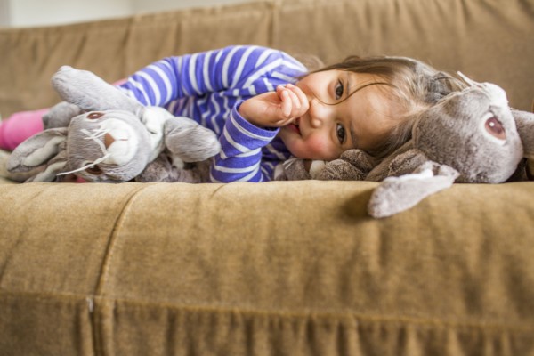 Caucasian girl laying on sofa sucking thumb