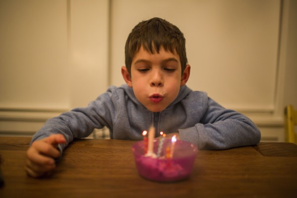 Mixed Race boy blowing candles on table