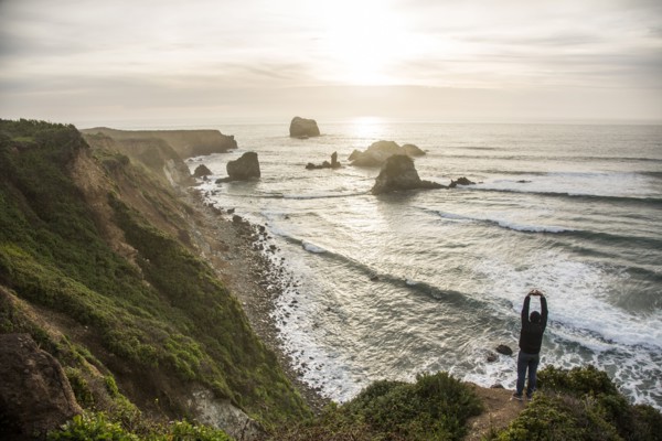 Caucasian man admiring scenic view of ocean sunset stretching arms