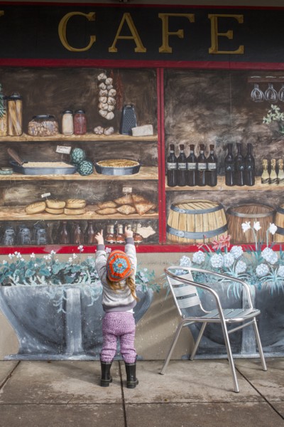 Caucasian girl standing on sidewalk admiring mural on wall