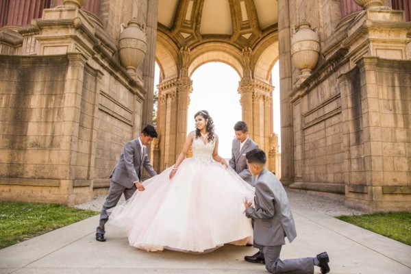 Hispanic boys holding skirt of girl