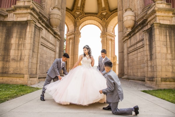 Hispanic boys holding skirt of girl