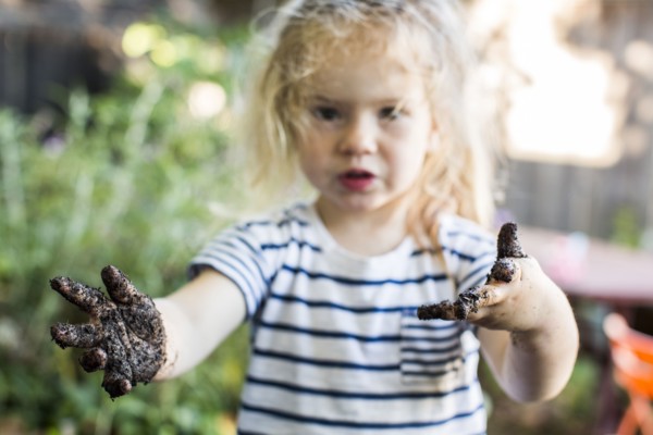 Caucasian girl with muddy hands in garden