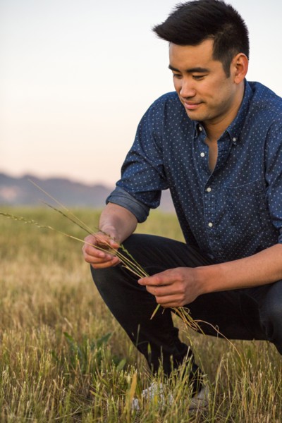 Smiling Chinese man crouching and holding grass in field