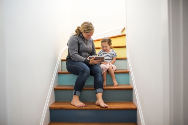 Caucasian mother and daughter using digital tablet on staircase