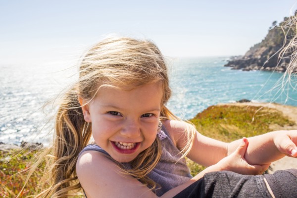 Wind blowing hair of smiling Caucasian girl near ocean