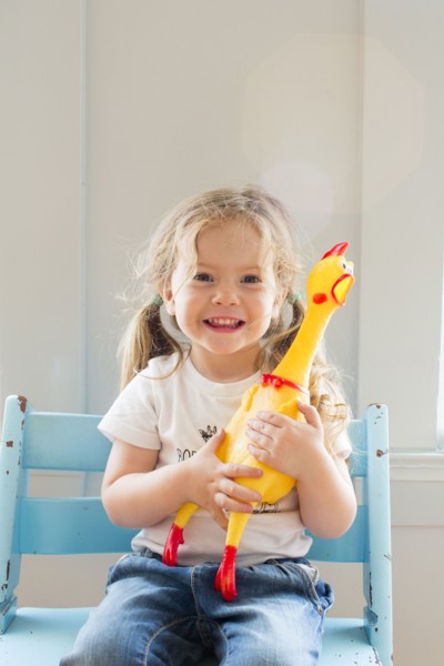Smiling Caucasian girl holding rubber chicken