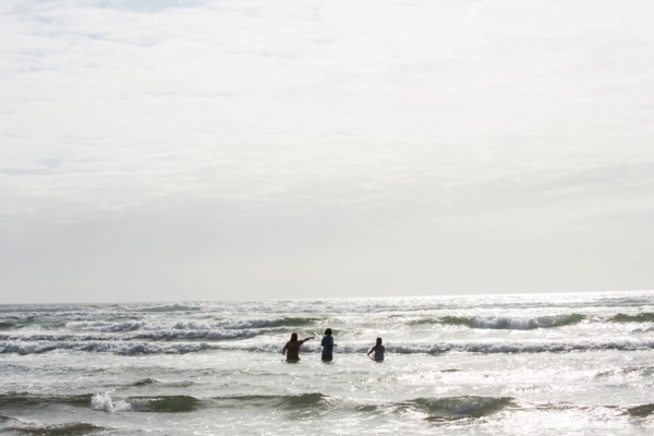 Caucasian people wading in ocean waves