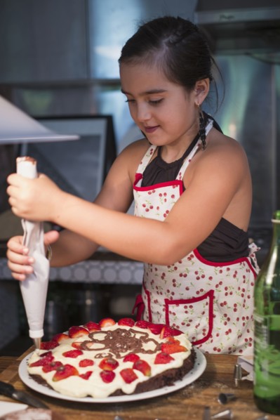 Caucasian girl decorating cake in kitchen