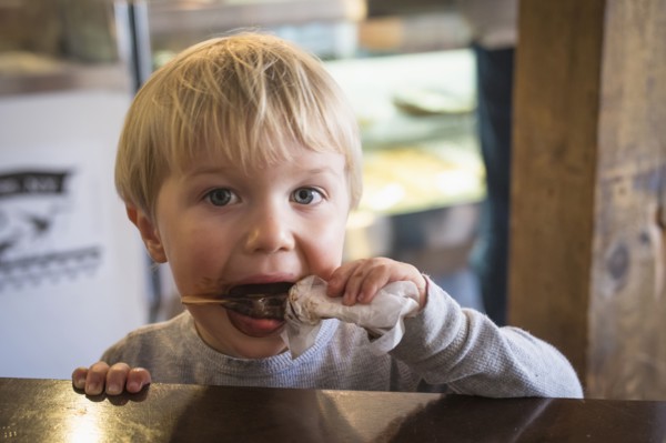 Messy Caucasian boy eating popsicle in kitchen