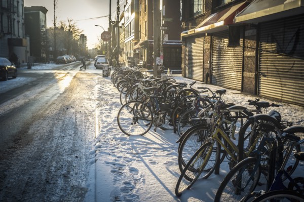 Bicycles parked in snow on city sidewalk