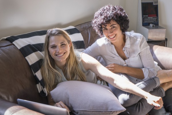 Caucasian lesbian couple smiling on sofa