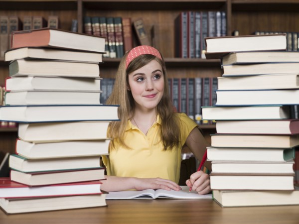 Student with stacks of books at desk in library