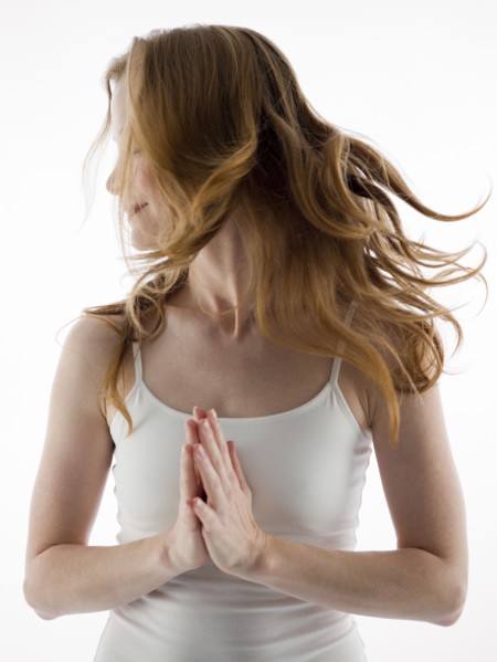 Caucasian woman tossing her hair with clasped hands