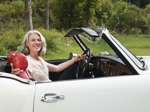 Older woman driving convertible in park