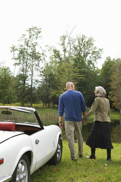 Rear view of couple holding hands by convertible in park