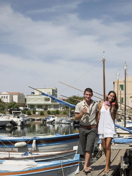 Couple walking on wooden dock in urban harbor