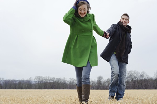 Caucasian couple walking in rural field
