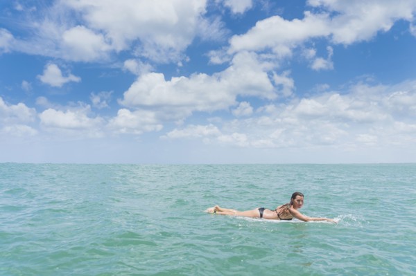 Caucasian woman paddling on surfboard in ocean