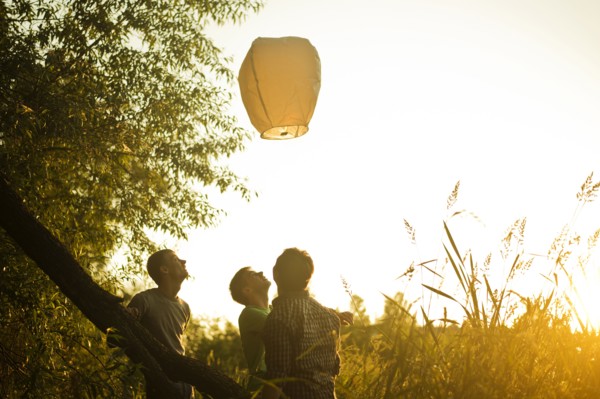 Caucasian men launching floating lantern outdoors