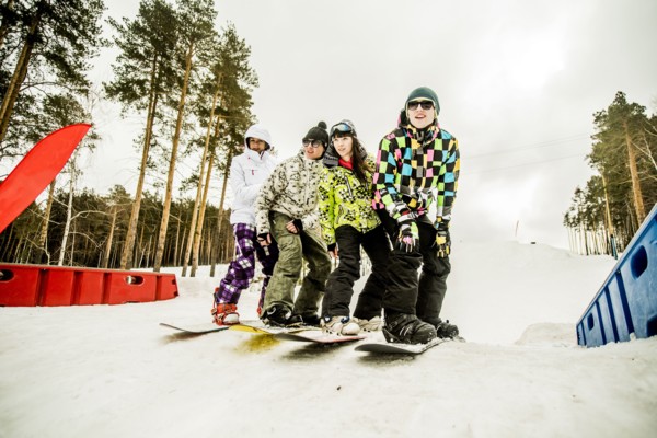 Caucasian couples snowboarding together on snowy hill