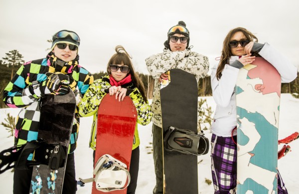 Caucasian couples holding snowboards in snow