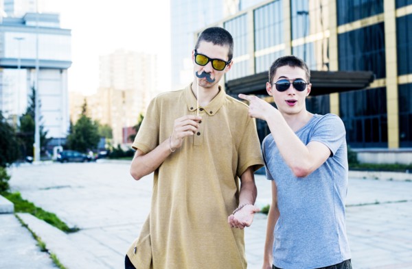Caucasian men playing with fake mustaches in city