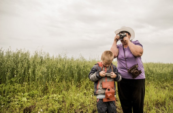 Caucasian mother and son taking photographs in rural field
