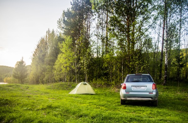 Car and tent at campsite in field