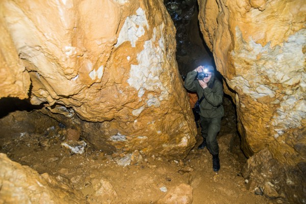 Caucasian man taking photograph in rock formation cave
