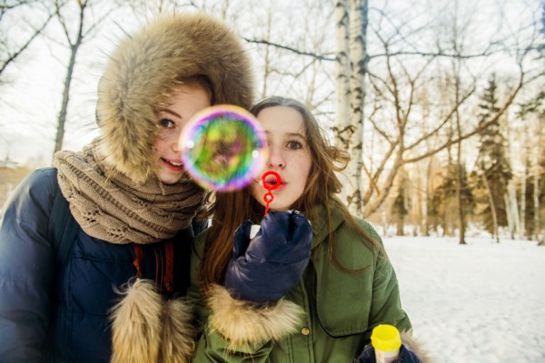 Caucasian women blowing bubbles in snowy field
