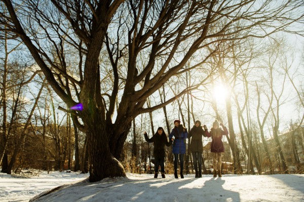 Caucasian girls standing neat tree in snowy field