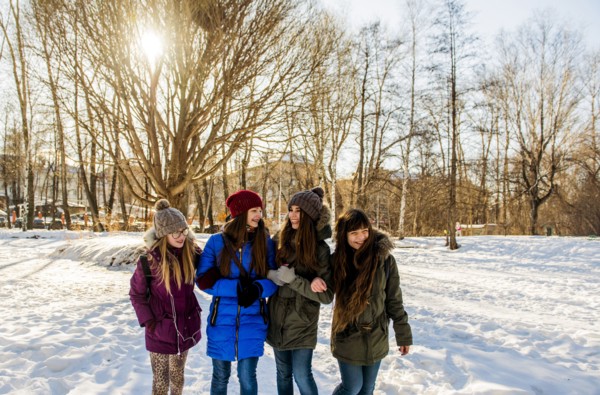 Caucasian girls arm in arm in snowy field