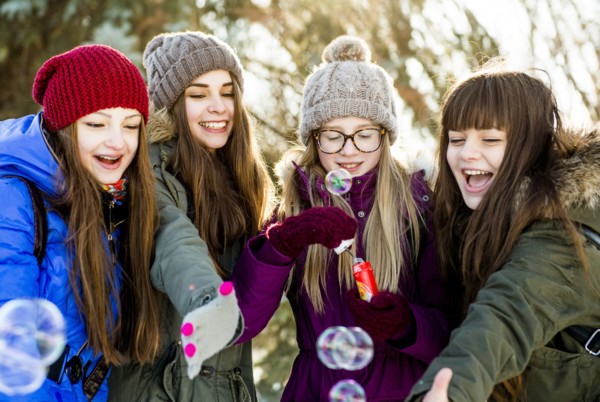 Caucasian girls blowing bubbles outdoors in winter
