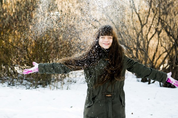 Caucasian girl throwing snow in field