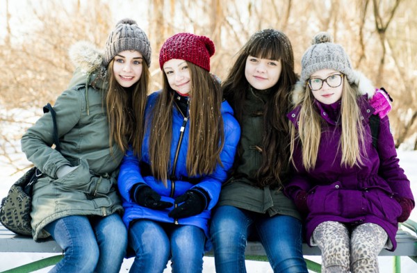 Caucasian girls smiling on bench in winter
