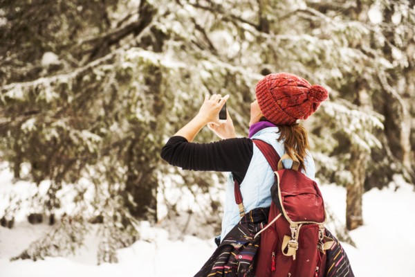 Caucasian woman photographing nature on snowy path