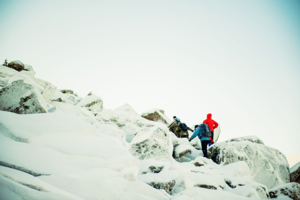 Caucasian hiker climbing snowy rock formations