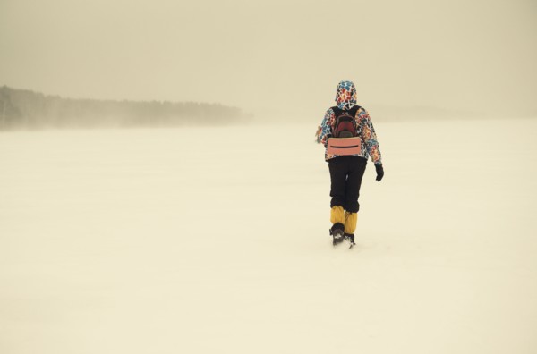 Caucasian hiker walking in snowy remote field