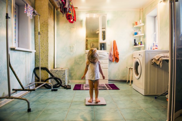 Caucasian girl standing on scale in bathroom