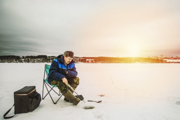 Man ice fishing in frozen lake