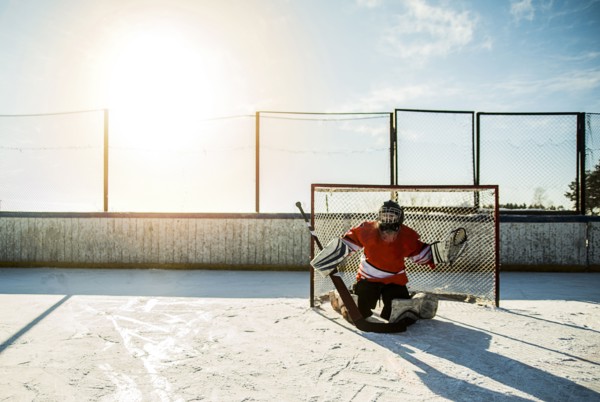 Caucasian boy playing goalie in ice hockey outdoors