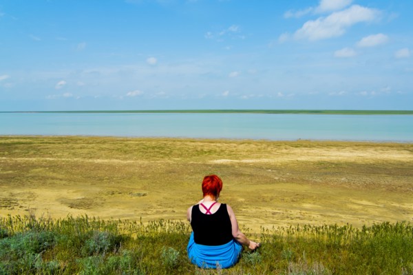 Woman sitting in grass near beach