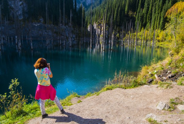 Caucasian woman photographing trees in lake