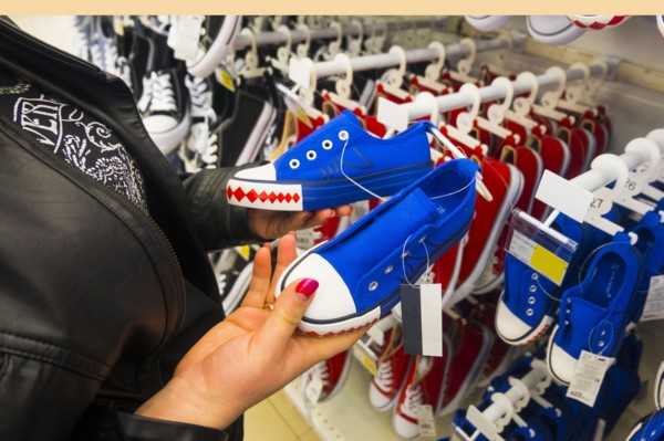 Hands of Caucasian woman holding sneakers in store
