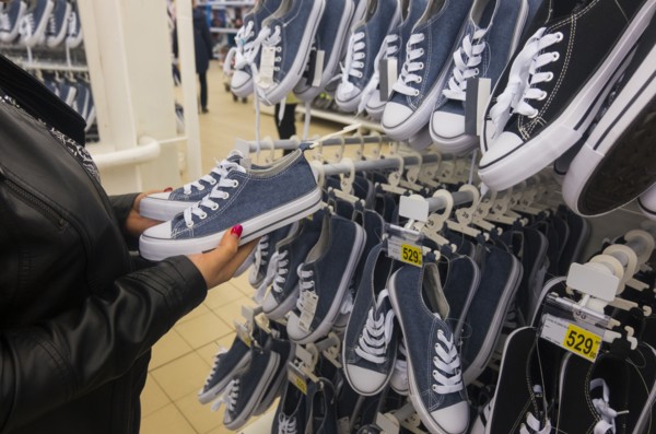 Hands of Caucasian woman holding sneakers in store