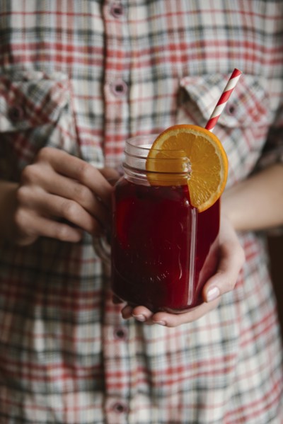 Woman holding glass of fruit tea with straw