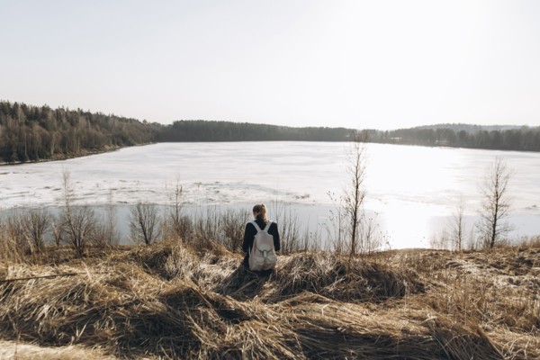 Middle Eastern woman sitting in grass near lake