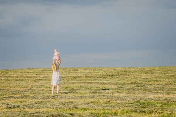 Mother lifting baby daughter in field